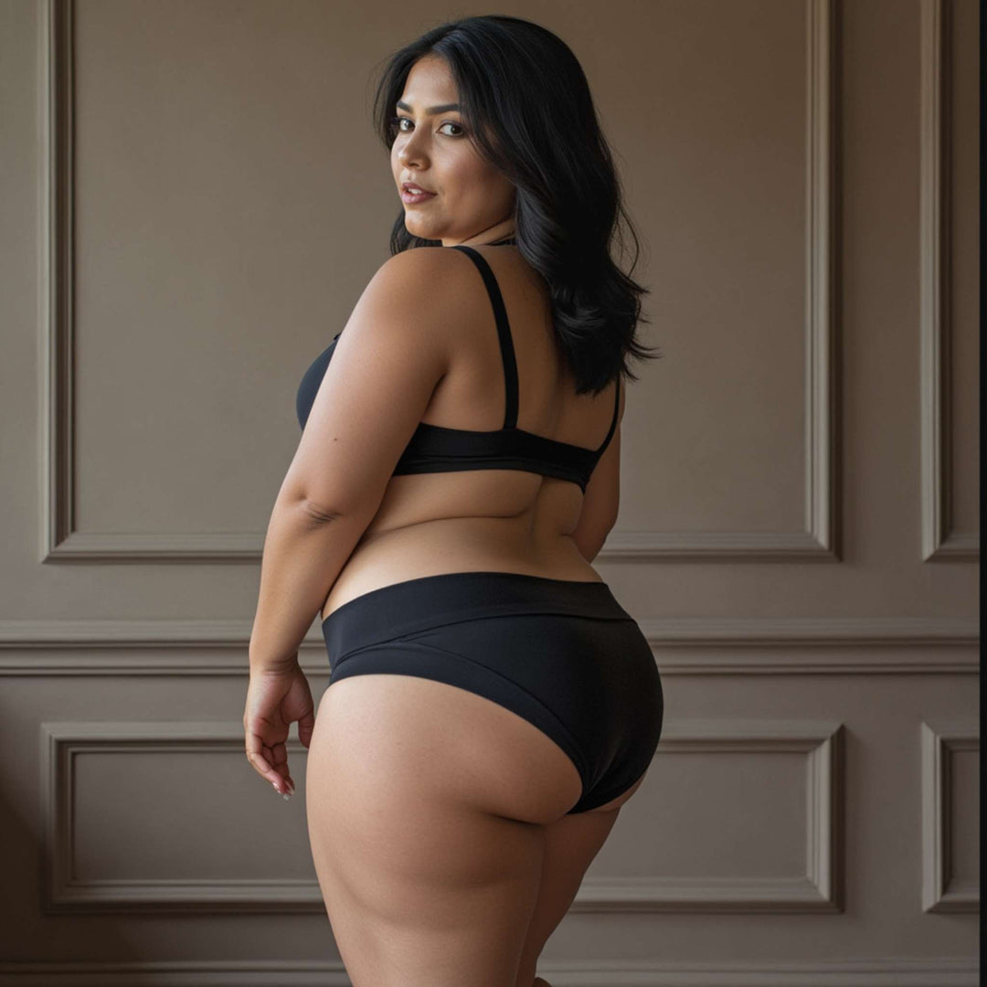 Woman stands with her back towards viewer showing back detail of the low-rise basic brief in obsidian black. Made from OEKO-TEX certified butter-soft blend fabric.