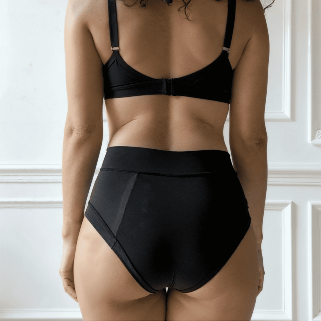 Detail of woman in her 30s with her back to the viewer wearing the high-waisted Emanate brief in Obsidian black made from OEKO TEX certified fabric