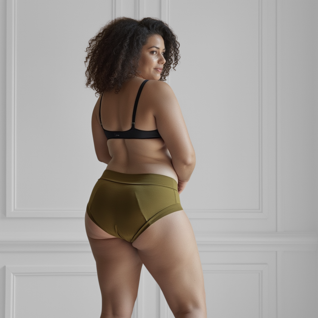 Woman in her 30s is facing away from the viewer wearing the High Waisted Basic brief in Moss green made from GOTS certified organic cotton