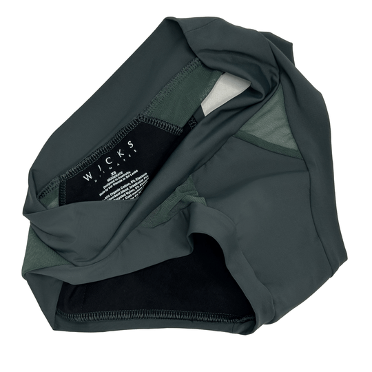 Artfully strewn flat lay image of the Swept Away brief in forest green