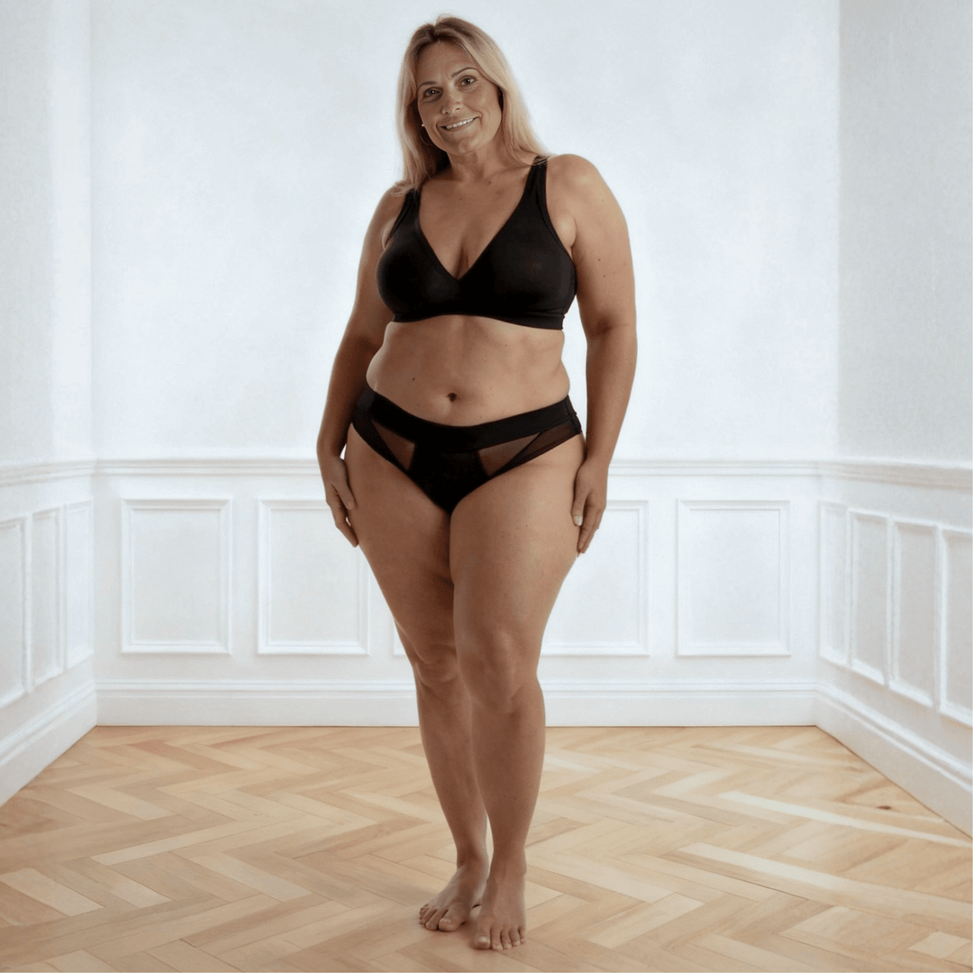 Woman in her 50s facing the viewer wearing the low-rise Swept Away brief in Obsidian Black made from OEKO TEX certified fabric
