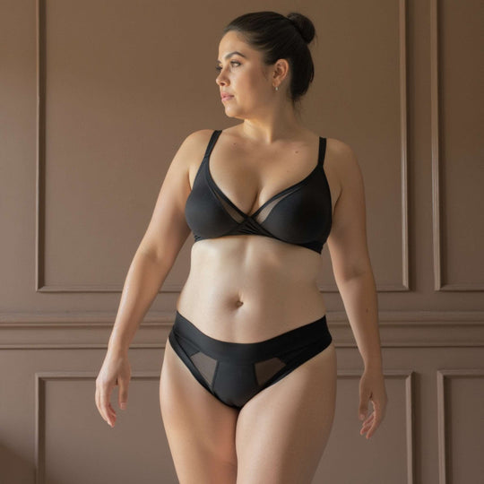 Woman wearing the low-rise Striation thong in obsidian black. For very light bladder leaks or spotting protection. OEKO-TEX certified butter-soft blend fabric.