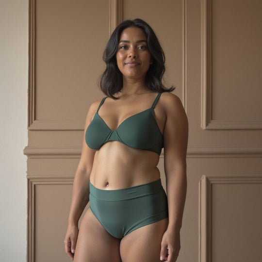 Woman facing forwards wearing high-waisted Anything But Basic brief in forest. For everyday wear with one absorbent layer but no waterproof layer. OEKO-TEX certified butter-soft blend fabric.